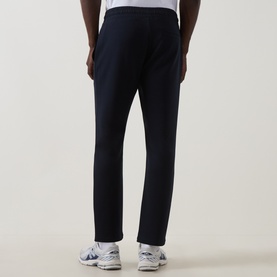 Model wearing Arne navy cotton blend sweatpants, back view, styled with white and blue trainers