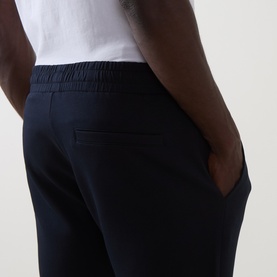 Model wearing Arne navy sweatpants, close-up of rear with elasticated waistband and back pocket detail, styled with white t-shirt.