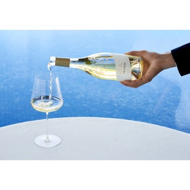 Chateau La Coste Le Blanc 500ml white wine being poured into a crystal glass, set against a bright blue background