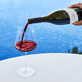 Chateau La Coste Le Rouge 75cl red wine being poured into a large crystal wine glass, poolside setting