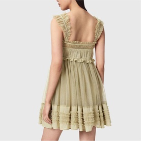 Model wearing sage green sleeveless mini dress with ruffle trim, smocked waist, and square neckline, seen from the back.