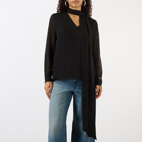 Model wearing House of Dagmar black wool blouse with tie neck detail and sheer sleeves, styled with wide-leg blue jeans.
