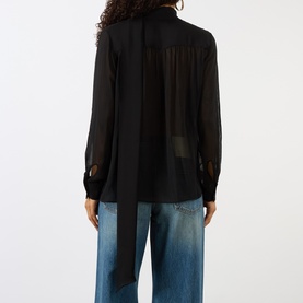 Model wearing House of Dagmar black sheer wool blouse, back view, with tie detail at neck and button cuffs, styled with blue wide-leg jeans