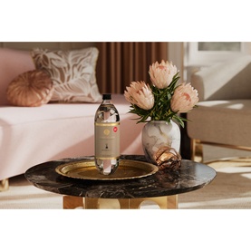 Rituals Cashmere Rose Refill Fragrance Sticks bottle on a marble tray beside pink protea flowers, styled in a warm living room setting.