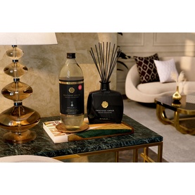 Rituals Precious Amber Refill Fragrance Sticks large bottle beside black reed diffuser with gold accents, styled on marble table in living room