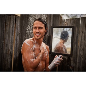 Model using Rituals Sport Shower Foam outdoors in shower, applying foamy body wash, reflection visible in mirror behind