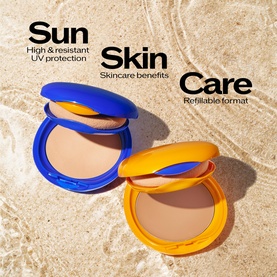 Shiseido Tanning Compact Foundation SPF10 in blue and yellow compact cases, open showing tan shade, on sandy surface with UV protection text