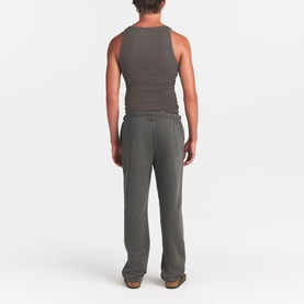 Model wearing Skims dark brown lounge trousers, rear view, paired with matching sleeveless top
