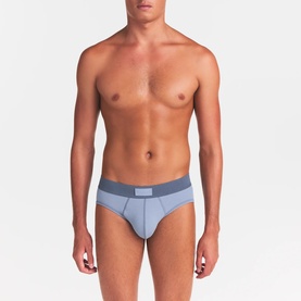 Model wearing Skims Briefs 3Pk in Nimbus Multi, light blue brief with contrast darker blue waistband and logo patch.