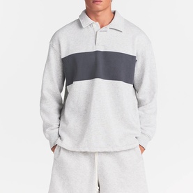 Model wearing Skims light heather grey colour-block polo sweatshirt with dark grey chest panel, styled with matching shorts.