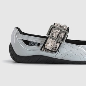 Close-up of a pale blue patent mary jane flat with snake-print buckle strap detail and black sole