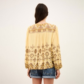 Model wearing Bash yellow embroidered blouse with balloon sleeves and ethnic print detail, styled with denim shorts.