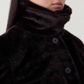 Model wearing Aligne brown faux fur jacket, close-up showing high funnel neck and black button fastening detail.