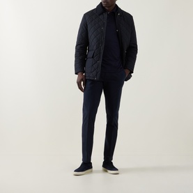 Model wearing Boggi Milano Navy Garment-Dyed Trousers, styled with a navy quilted jacket and navy top, paired with dark trainers.