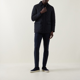 Model wearing Boggi Milano Garment-Dyed Trousers in navy, styled with a dark quilted jacket and navy suede trainers.