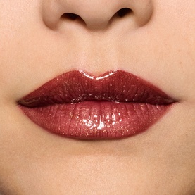 Model wearing MAC Lip Gloss in Damnsel, a deep red shade with glossy shimmer finish, shown close up on lips.