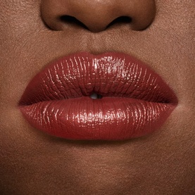 MAC Lustreglass Sheer-Shine Lipstick in Roan of Arc worn on lips, showing deep terracotta-brown glossy finish