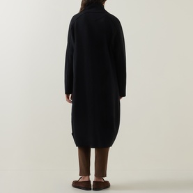 Model wearing Oska Fold-Down Wrap Coat in black, rear view, showing balloon hem, exposed seams and knit construction, styled with brown trousers and
