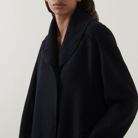 Model wearing Oska Fold-Down Wrap Coat in black, featuring a fold-down collar, rounded shoulders, and relaxed oversized silhouette.