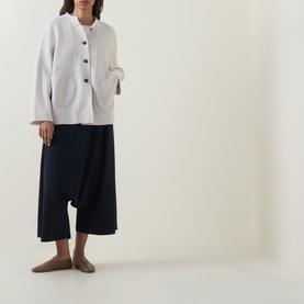 Model wearing Oska Patch Pocket Knitted Cardigan in ecru with round neck and patch pockets, styled with navy wide-leg trousers and nude flat shoes.