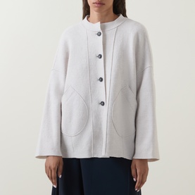 Model wearing Oska Patch Pocket Knitted Cardigan in ecru with round neck, button front, patch pockets and exposed seam detail.