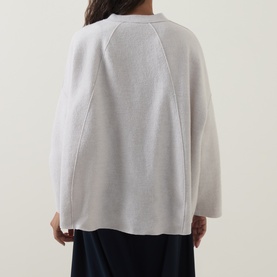 Model wearing Oska Patch Pocket Knitted Cardigan in ecru, rear view showing dropped shoulders, long sleeves and exposed seam detailing.
