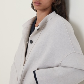 Model wearing Oska Patch Pocket Knitted Cardigan in ecru, showing button fastening, exposed seam detail and round neckline, styled over navy top.