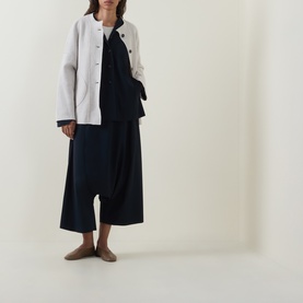 Model wearing Oska Patch Pocket Knitted Cardigan in ecru with navy wide-leg trousers and taupe flat shoes.
