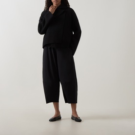 Model wearing Oska Fold-Down Wrap Jacket in black with fold-down collar, styled with matching wide-leg trousers and black loafers.