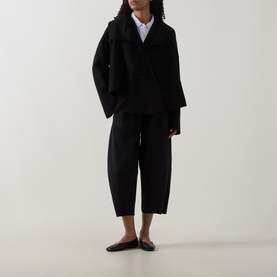 Model wearing Oska Fold-Down Wrap Jacket in black with cropped trousers and black flat mules.