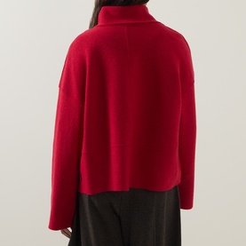 Model wearing Oska scarlet wool jacket, rear view, showing relaxed cropped silhouette and funnel neck, styled with dark trousers