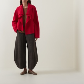 Model wearing Oska scarlet wool jacket, styled with dark wide-leg trousers and a brown fitted top.