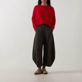 Model wearing Oska Rib-Knit Sweater in Scarlet with crew neck and dropped shoulders, styled with dark wide-leg trousers and beige flats.