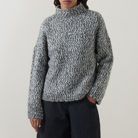Model wearing Oska Chunky-Knit Sweater in black, mock neck, dropped shoulders, textured knit, styled with dark wide-leg trousers.