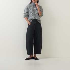 Model wearing Oska Chunky-Knit Sweater in black with mock neck and dropped shoulders, styled with wide-leg dark trousers and black flat shoes.