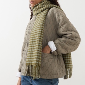 Model with Oska Houndstooth Fringed Scarf in Meadow, wrap-around style with fringed edges, styled with quilted jacket