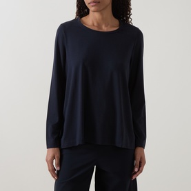 Model wearing Oska Solid Long-Sleeved Top in navy, with crew neckline, long sleeves and fluid flared hem, styled with navy trousers.