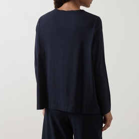 Model wearing Oska Solid Long-Sleeved Top in navy, rear view, with crew neck, long sleeves, flared hem, paired with navy trousers.