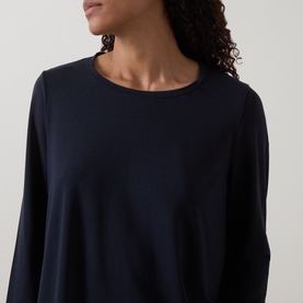 Model wearing Oska Solid Long-Sleeved Top in navy, featuring crew neckline, long sleeves and fluid silhouette with slightly flared hem.
