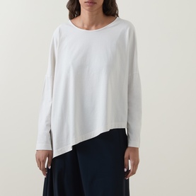 Model wearing Oska Asymmetric Long-Sleeved Top in ecru with round neckline and asymmetric hem, styled with navy wide-leg trousers.