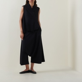 Model wearing Oska black sleeveless top with wide-leg cropped trousers and flat black loafers.