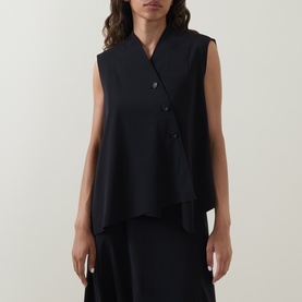 Model wearing Oska black sleeveless asymmetric top with double-button fastening, styled with wide-leg black trousers