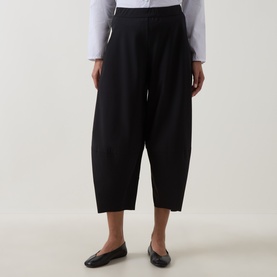 Model wearing Oska Wide Cropped Trousers in black, mid-rise, wide-leg silhouette, styled with a white shirt and black ballet flats.