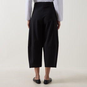 Model wearing Oska Wide Cropped Trousers in black, wide-leg silhouette with elasticated waistband, styled with a white top and black flat shoes.