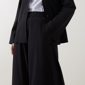 Model wearing Oska Wide Cropped Trousers in black, wide-leg silhouette with elasticated waist, styled with a black blazer and white shirt.