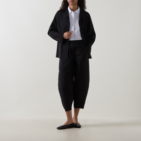Model wearing Oska Wide Cropped Trousers in black, styled with a black linen blazer, white shirt and black ballet flats.