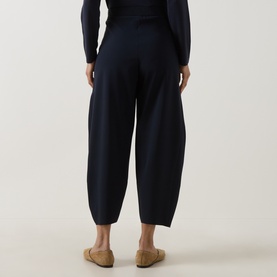 Model wearing Oska Straight Cropped Trousers in navy, cropped barrel-leg silhouette with elasticated waistband, styled with navy knit top and tan