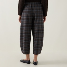 Model wearing Oska choco check trousers, cropped barrel-leg silhouette with elasticated waist, styled with black flat shoes.