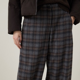 Model wearing Oska choco check wide-leg trousers in wool blend, styled with a dark quilted jacket.