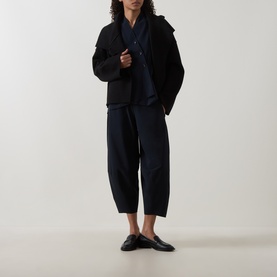 Model wearing Oska Wide Cropped Trousers in navy, wide-leg silhouette, styled with black jacket, navy scarf and black mules.